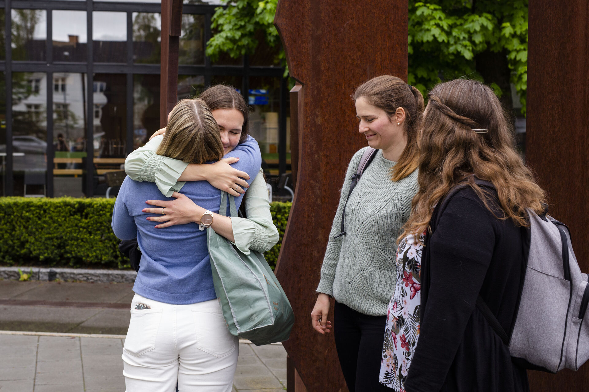 To kvinnelige studenter omfavner hverandre mens to andre ser på utenfor studiested Hamar.