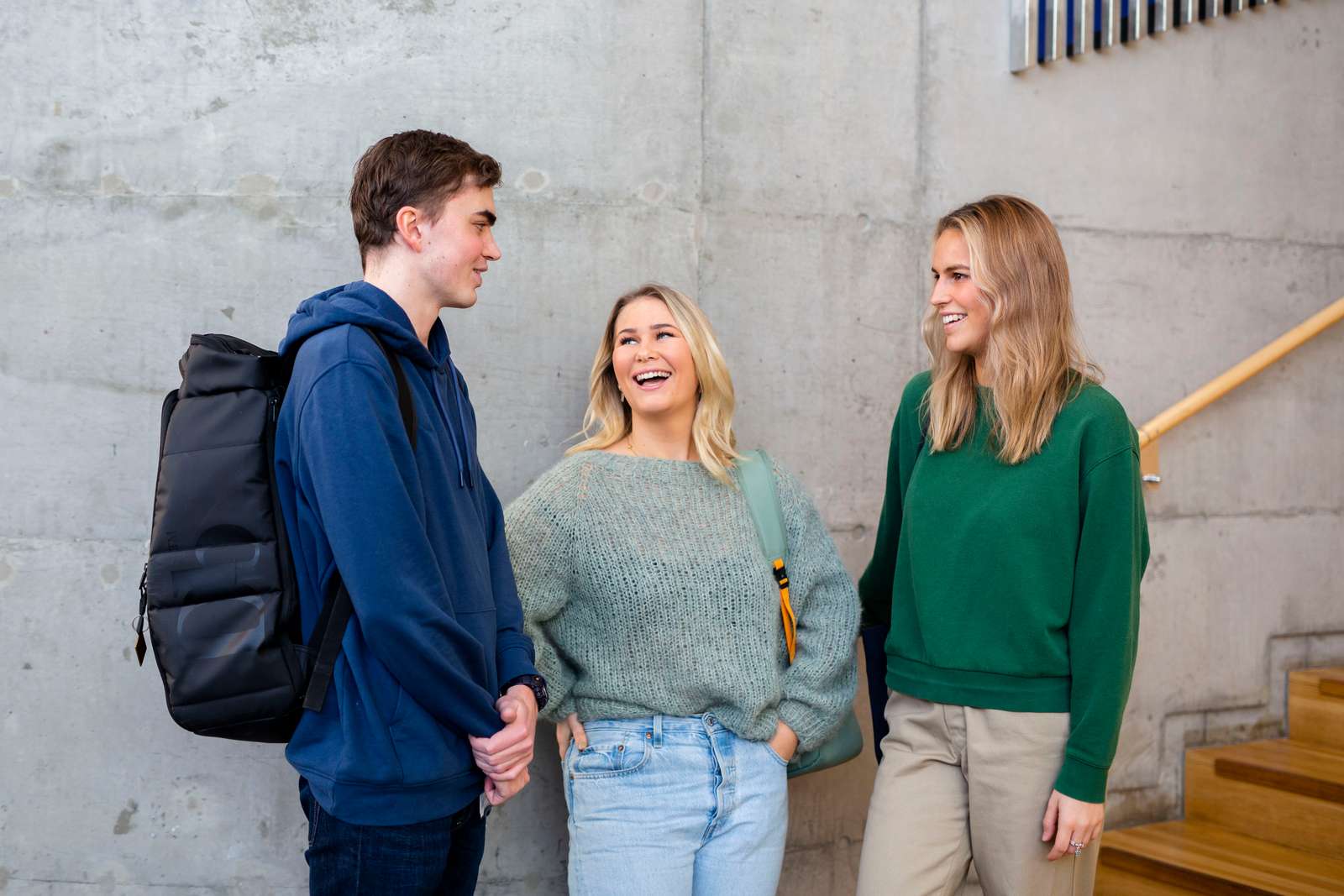 En mannlig og to kvinnelige studenter i munter samtale.
