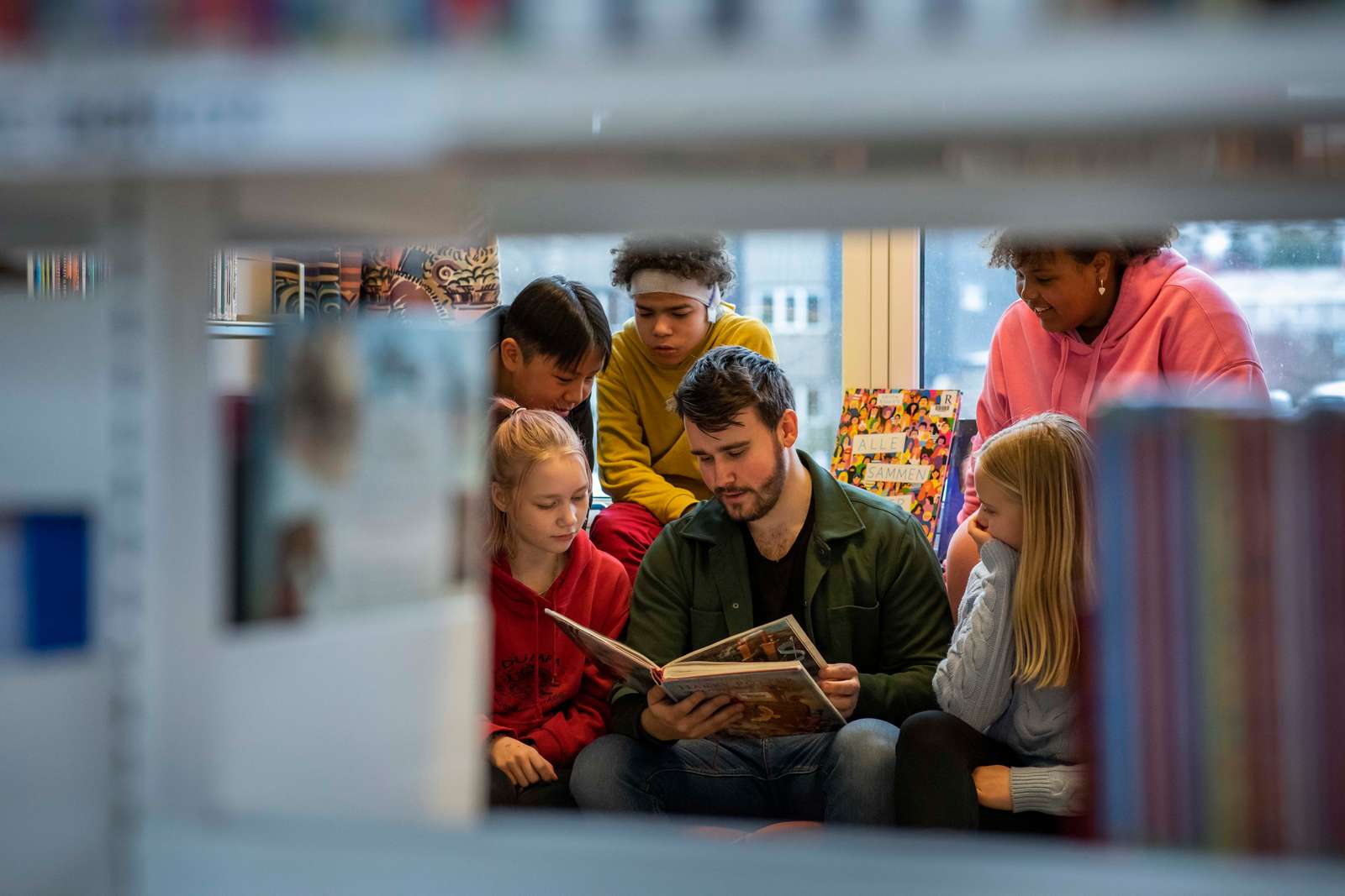 Mannlig lærer sitter og leser for elever