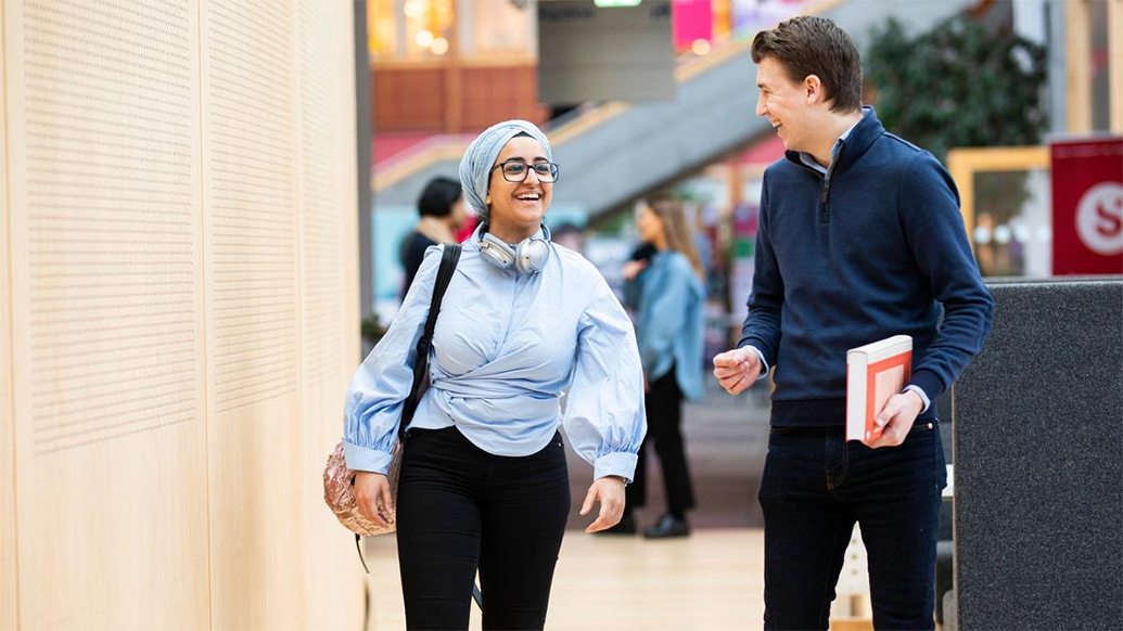 Female and male student talking to eachother and laughing.