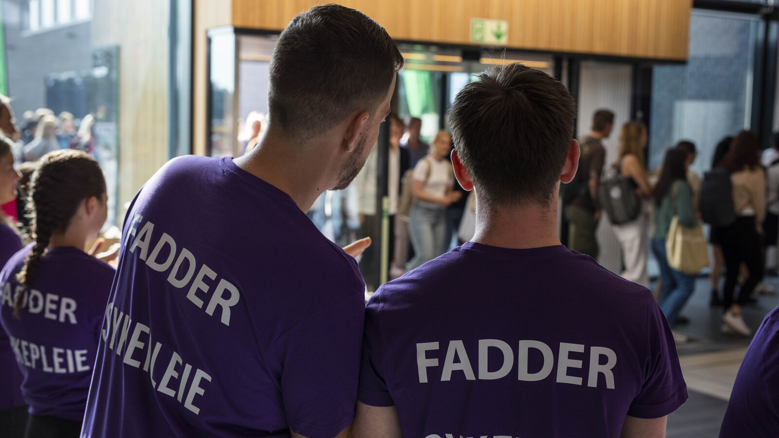 Bakhodet til to gutter med lilla fadder t-skjorter på seg. De tar imot nye studenter.