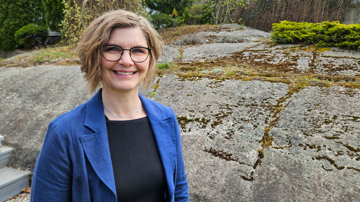Hilde med blå jakke og svart genser mot et svaberg