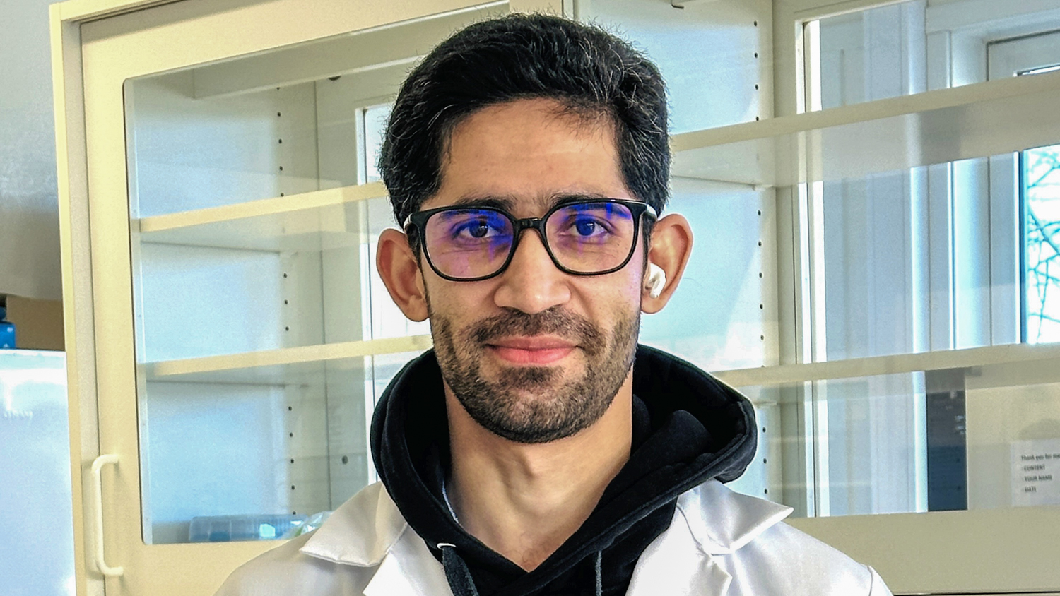 Jawad i labfrakk with a black hoodie and lab coat in the lab