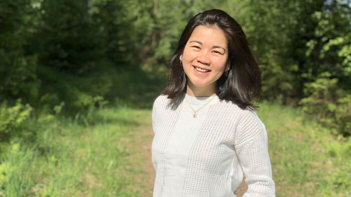 A picture of Jennifer on a green field in front of some trees