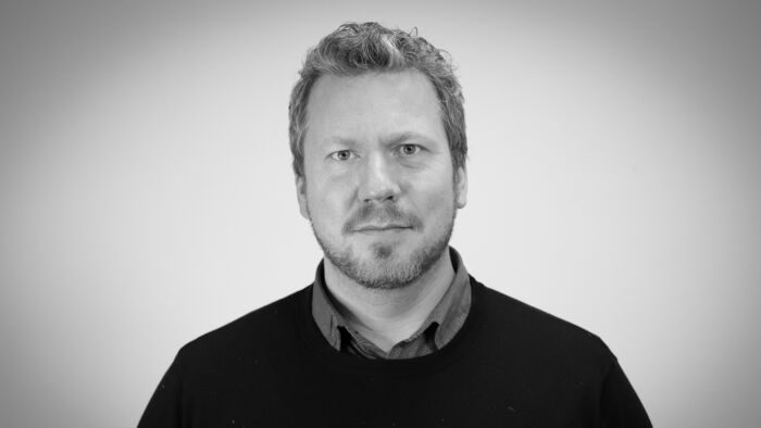 Svart-hvitt portrettbilde av Eirik Skjelstad mot en hvit vegg