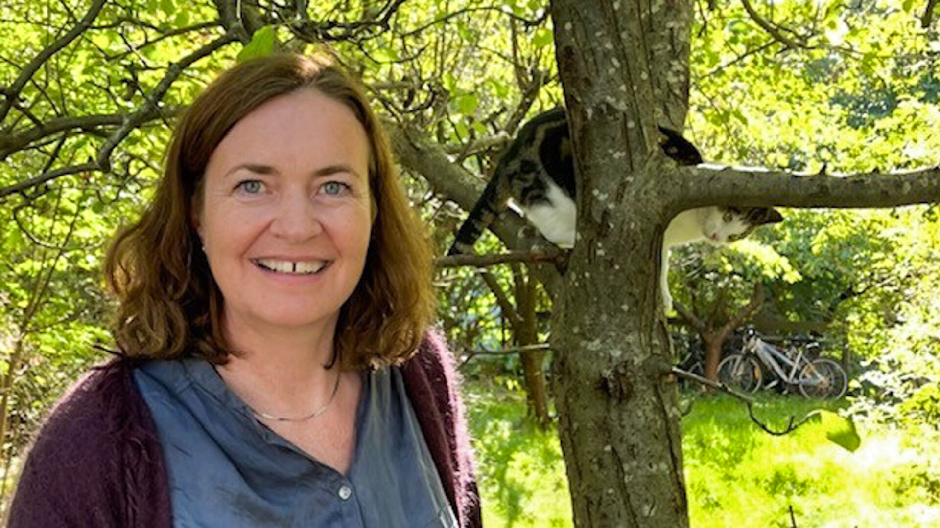 Dame foran et tre med en katt i.