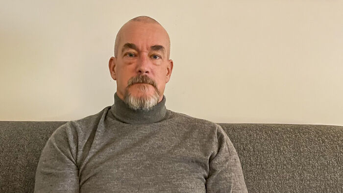 Portrettbilde av Jan-Freddy sittende i en grå sofa med grå genser