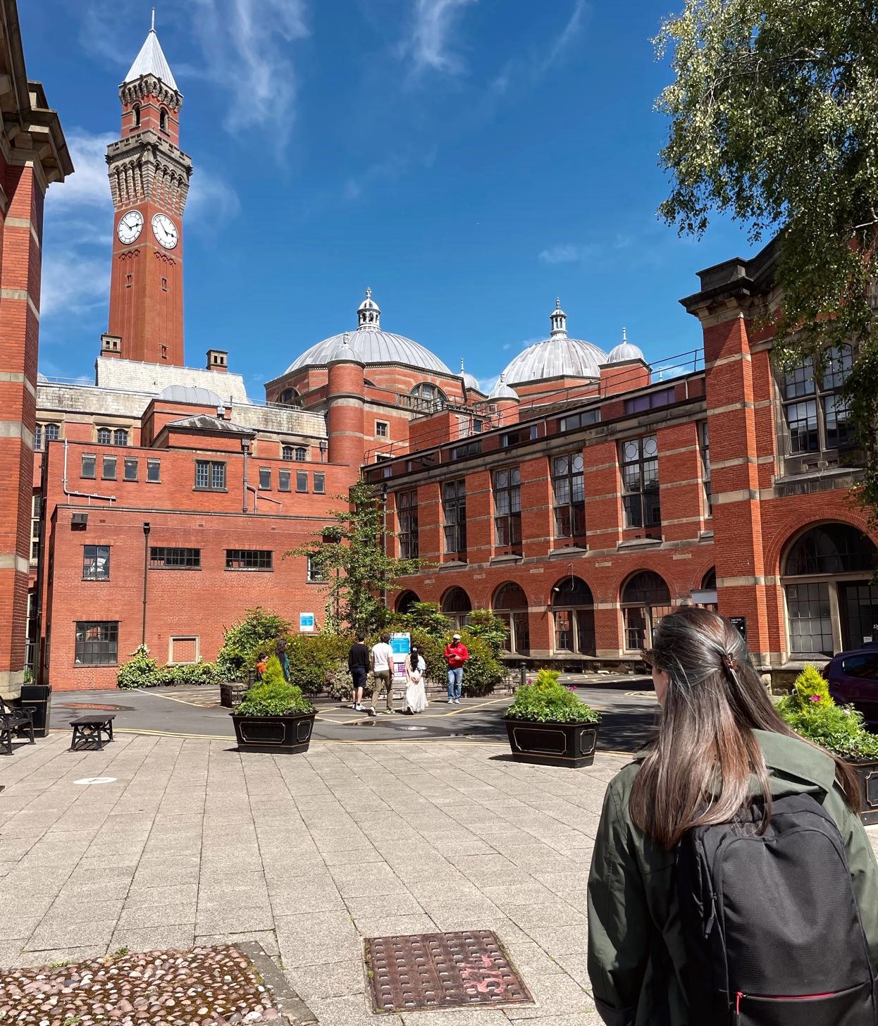 A woman studies the red brick buildings of the University of Birmingham.