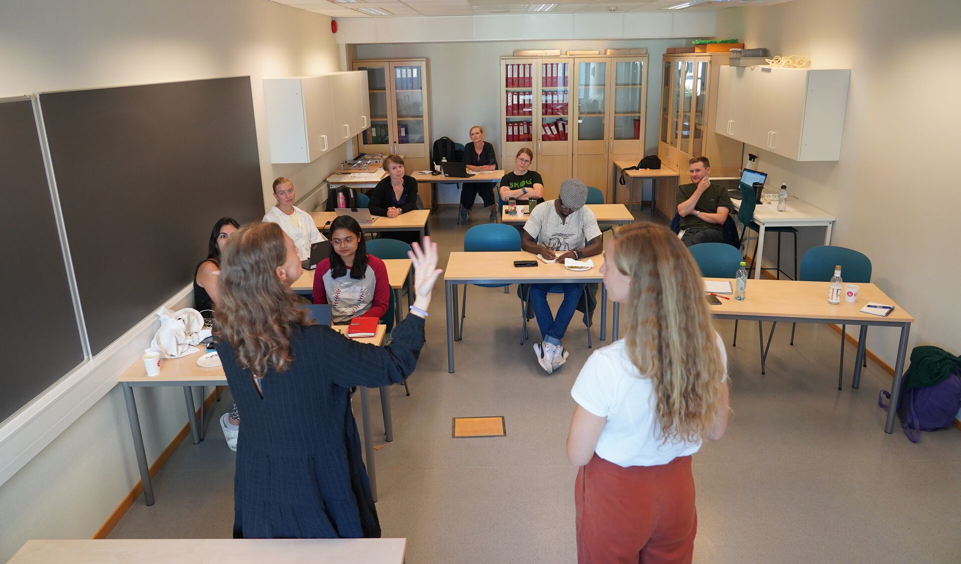 To lærere står foran folk i et klasserom