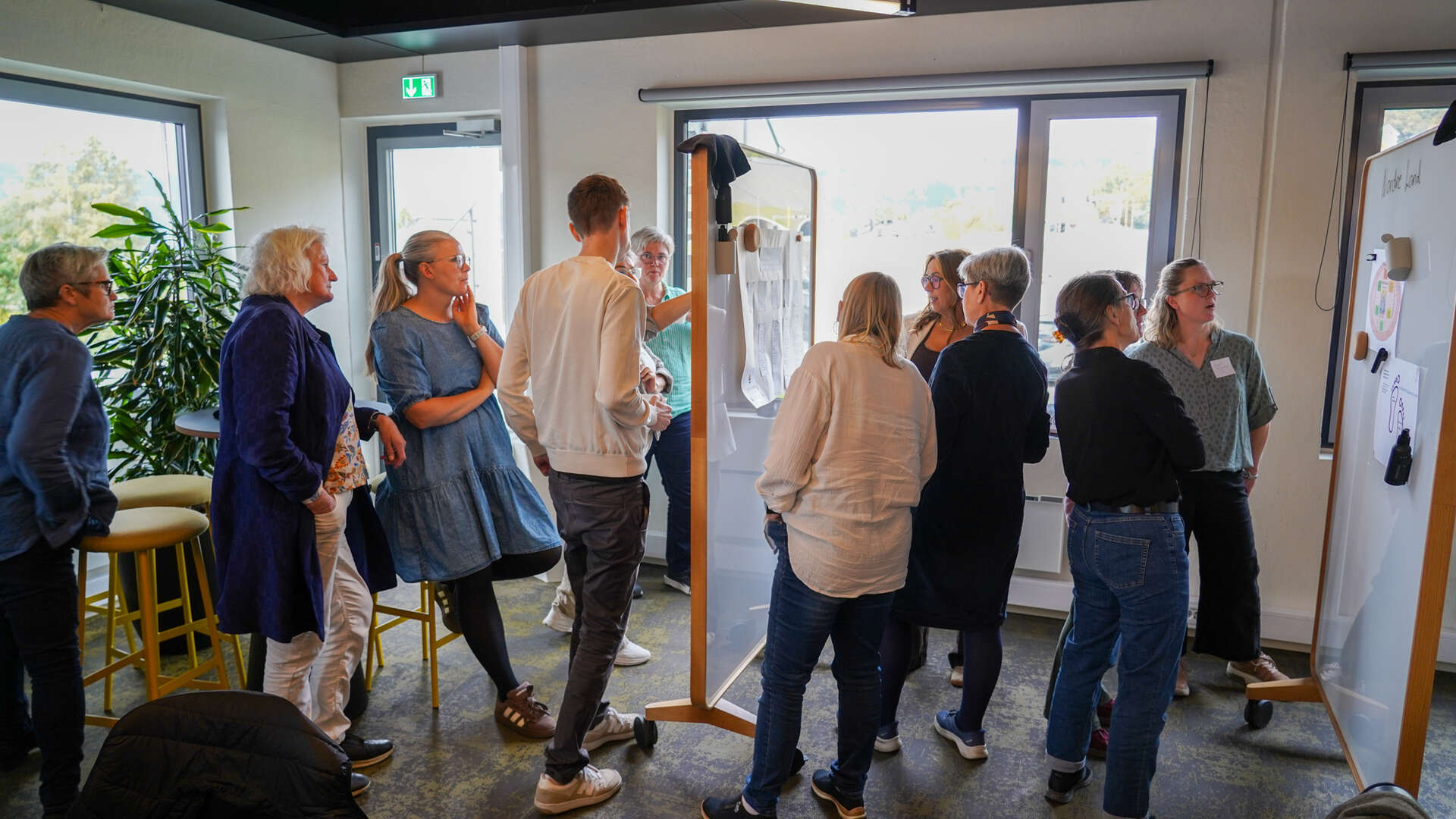 Folk står rundt to skillevegger og diskuterer hva de ser