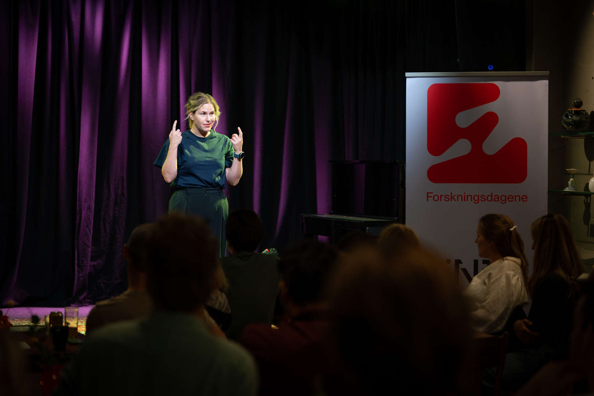 Ung dame står på en scene og snakker for publikum