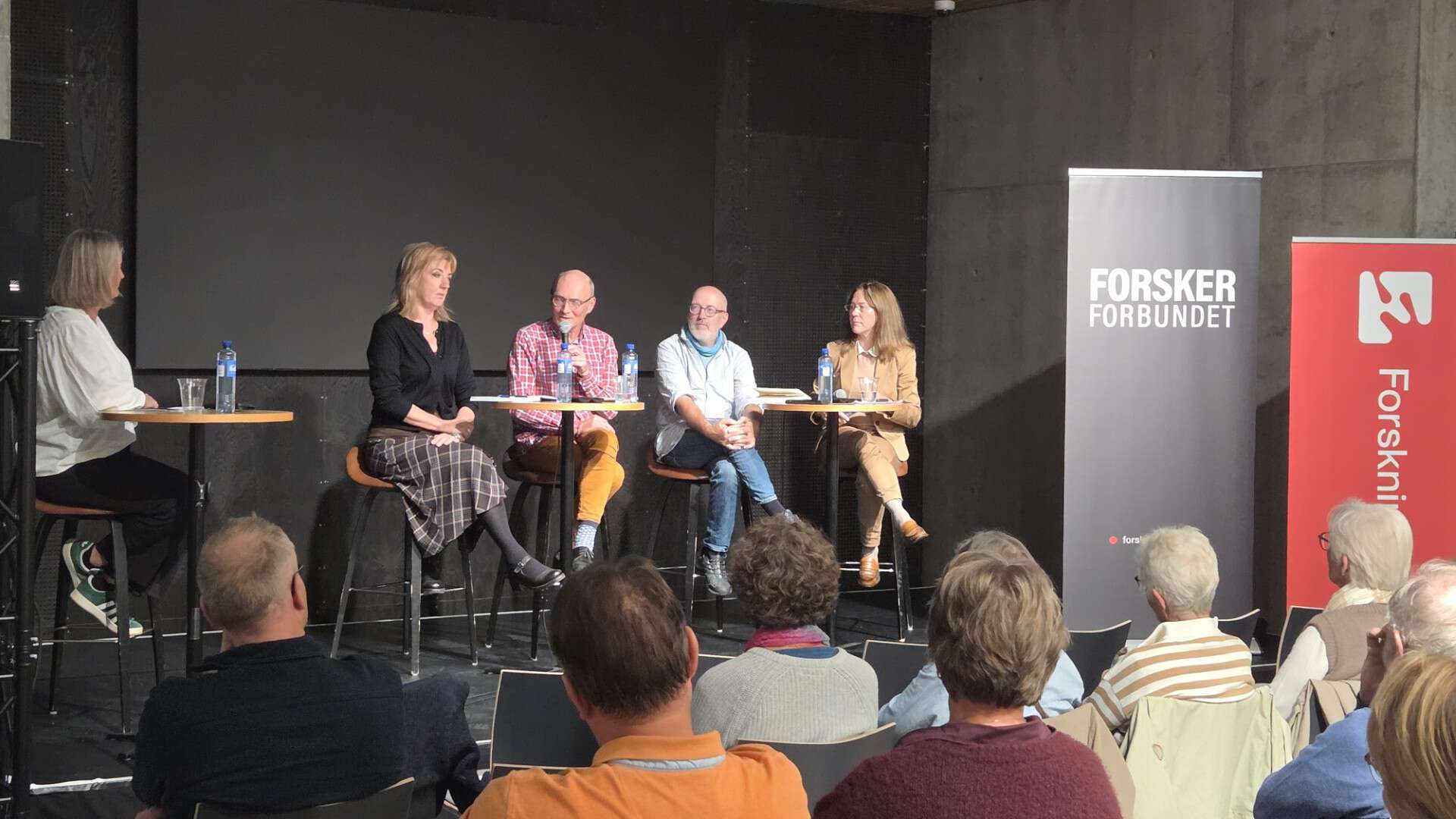 Fire personer i en panelsamtale på en scene