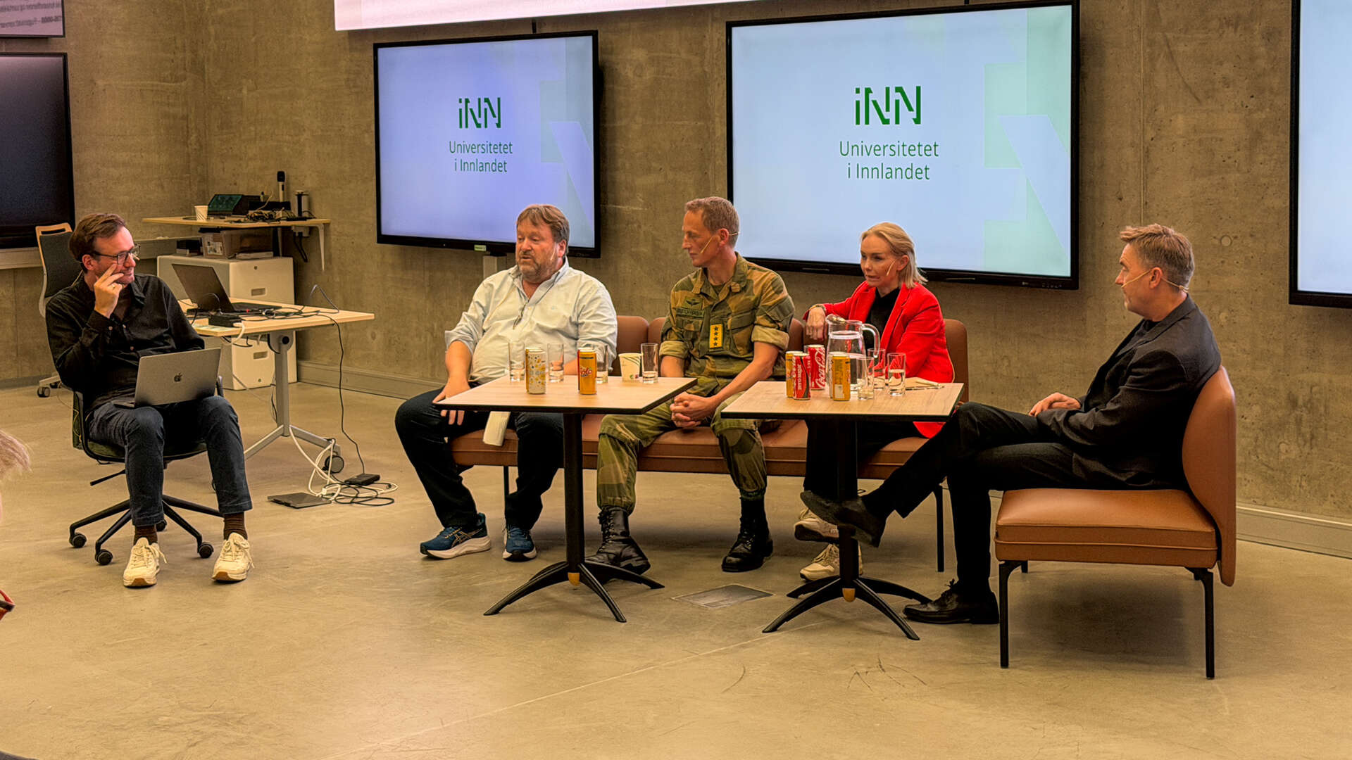 Fem personer har en panelsamtale i en sofa foran publikum