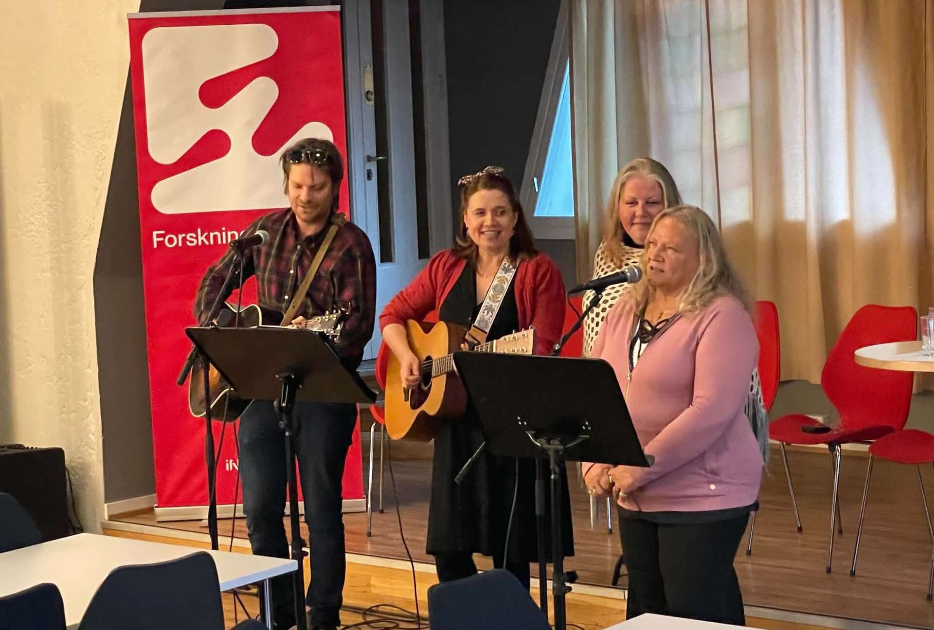 Fire personer spiller musikk fra en scene
