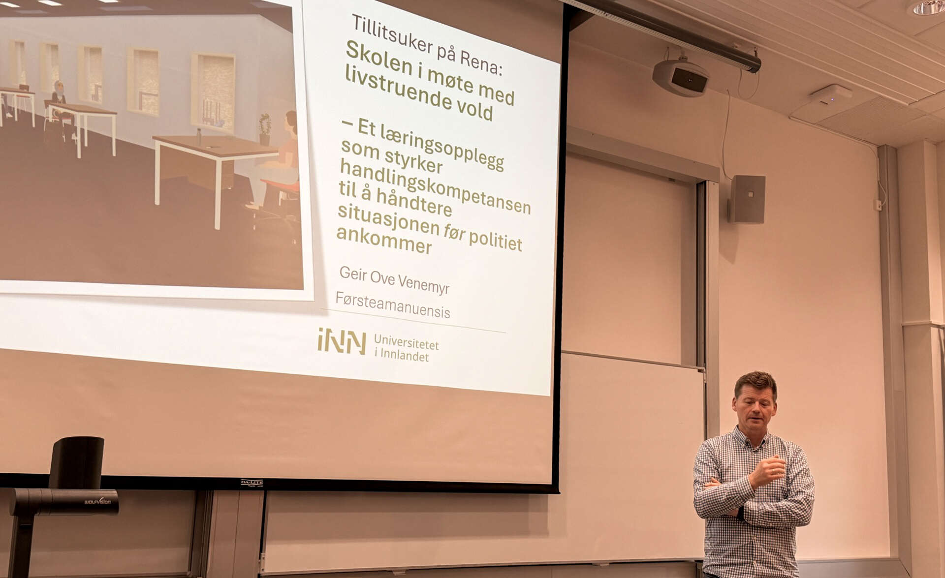 Mann står foran stor skjerm og holder forelesning