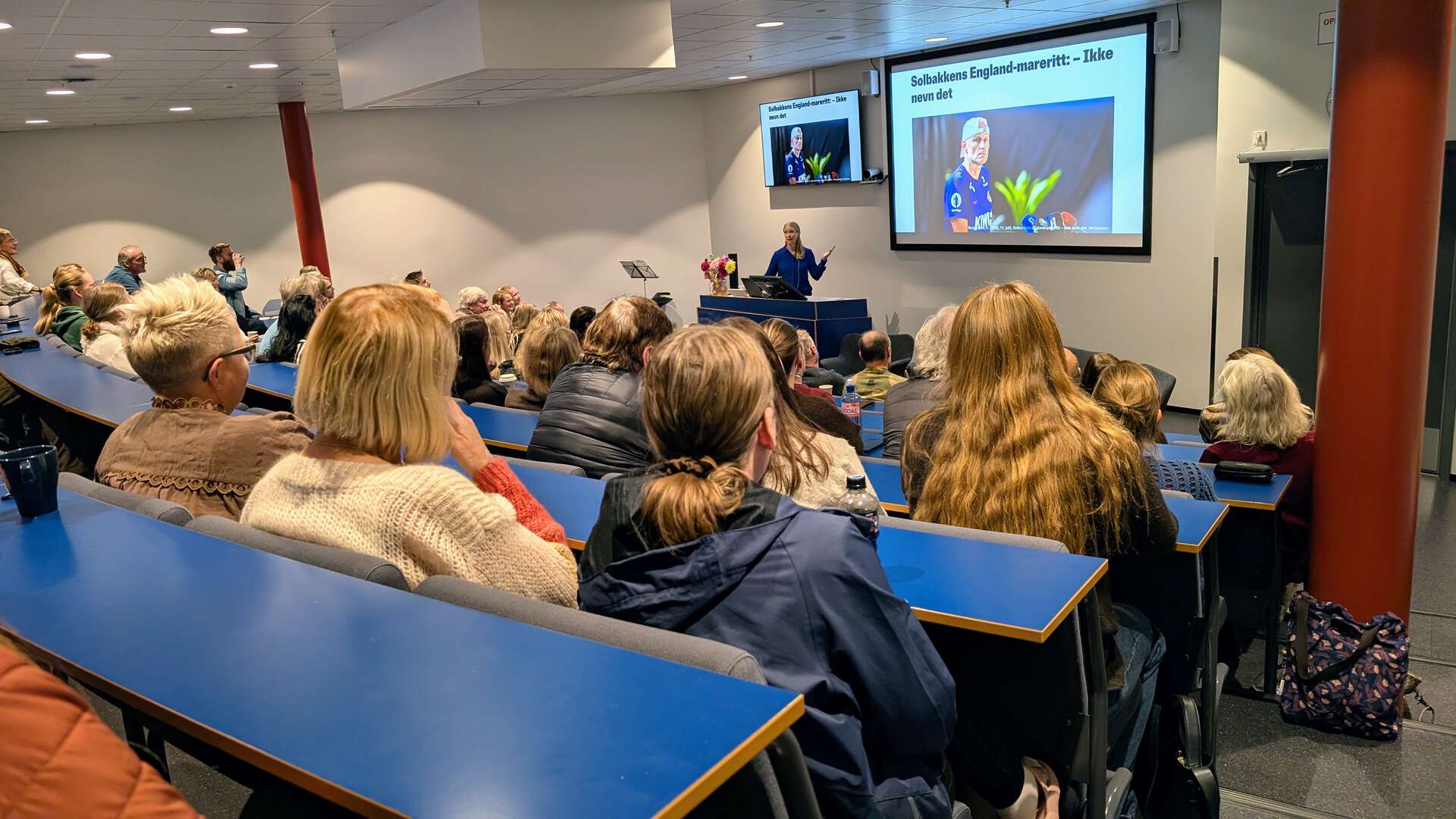 Mange folk i et auditorium ser mot skjerm