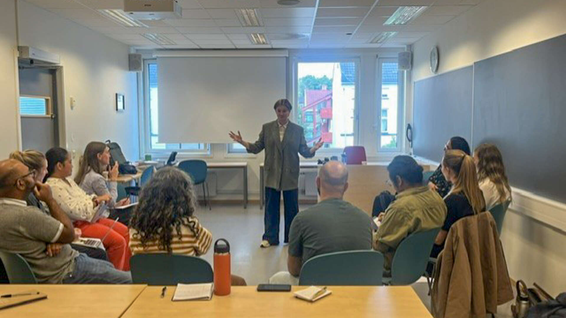 En dame står foran en gruppe folk i et klasserom