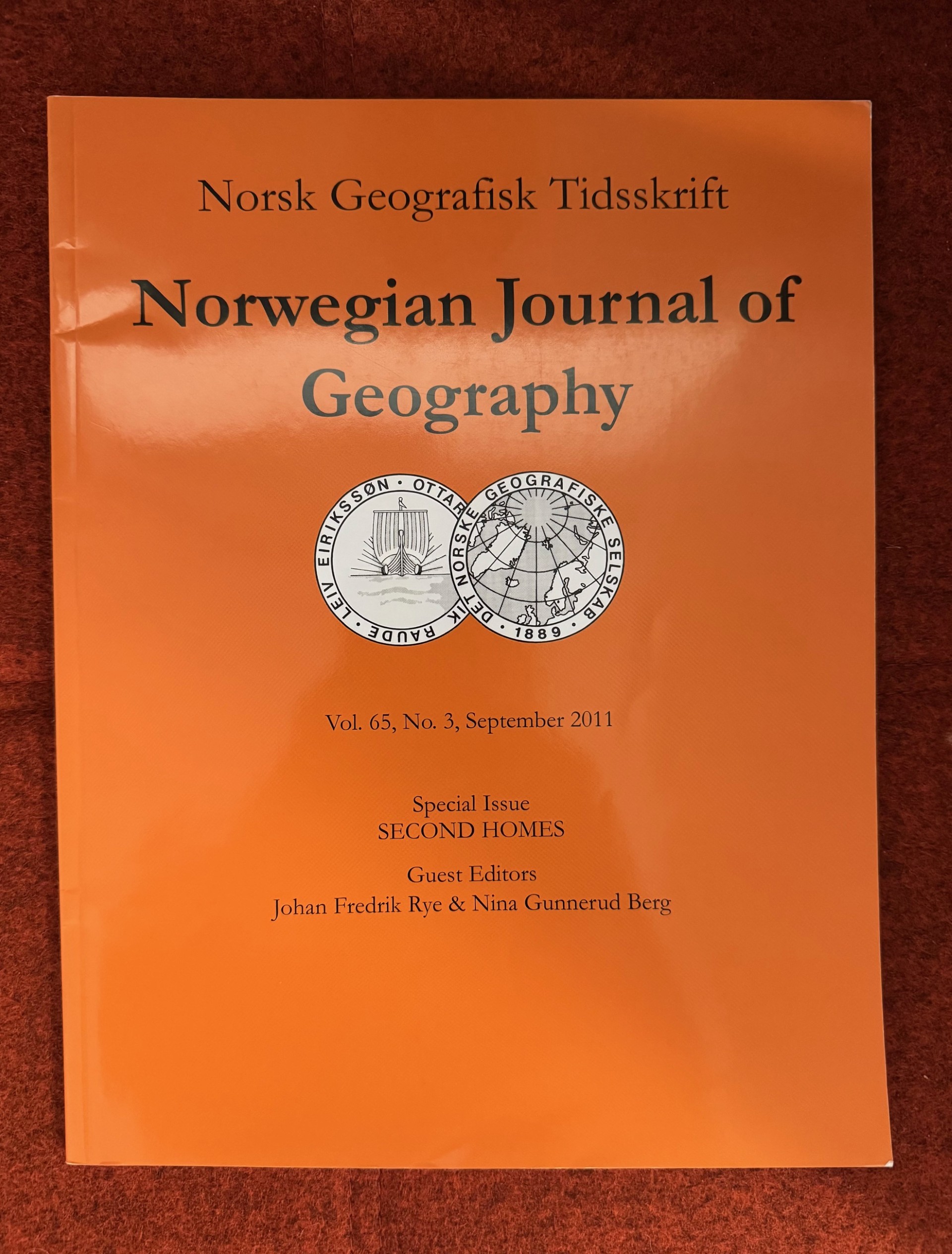 Bilde av et orasnej cover til tidsskriftet Norsk Geografisk Tidsskrift