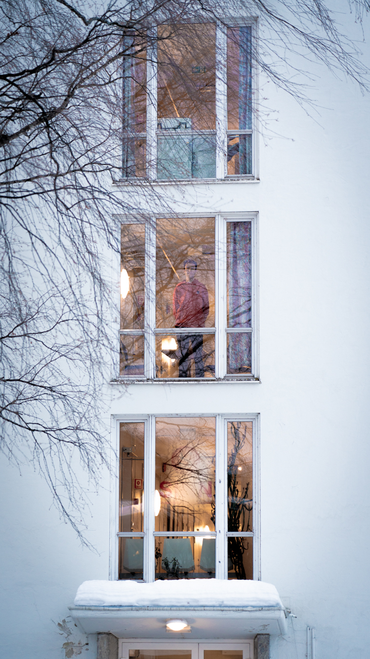 A building with three windows is shown from the outside. Stian is in the middle window