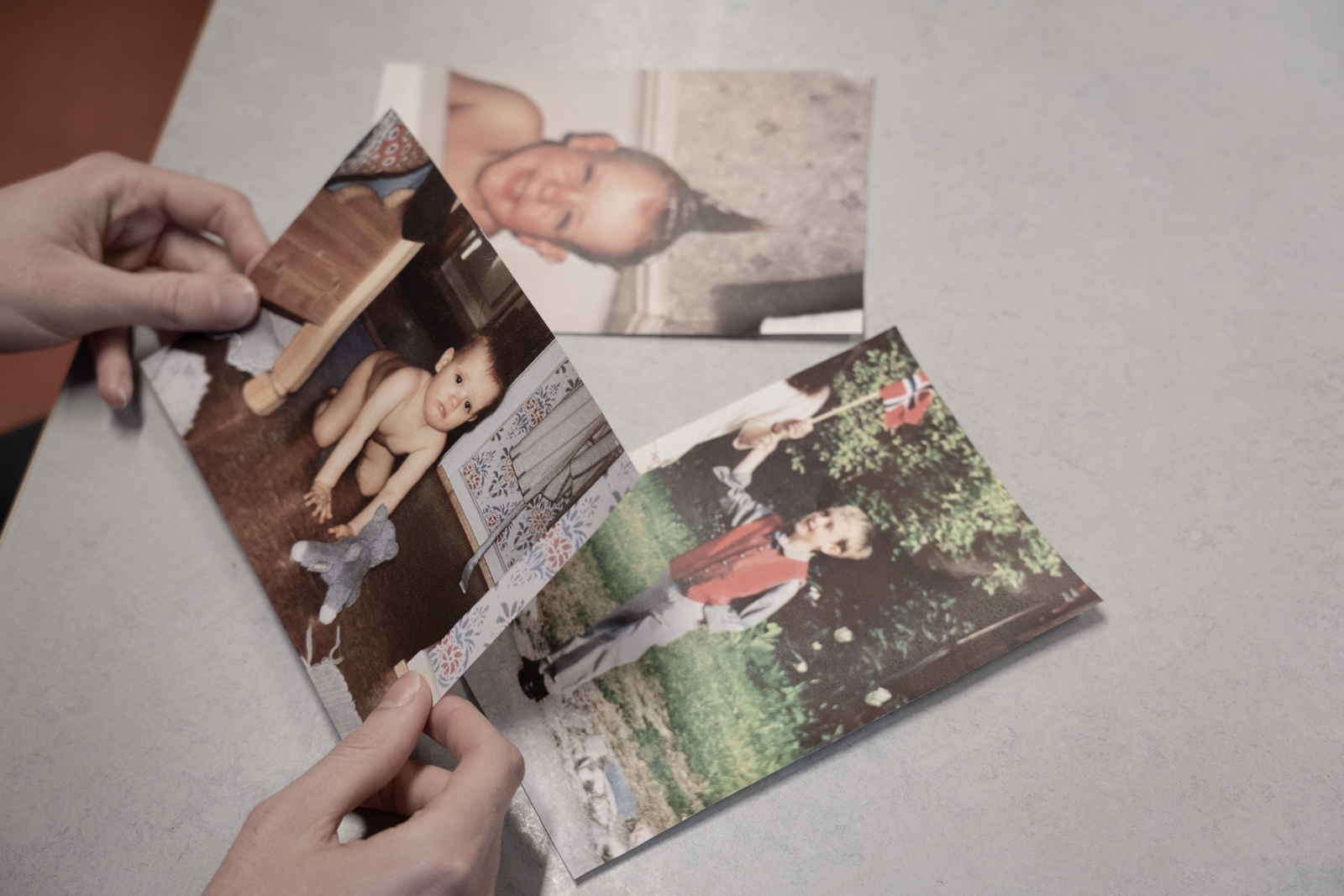 Hands holding a collection of pictures from Stian's childhood