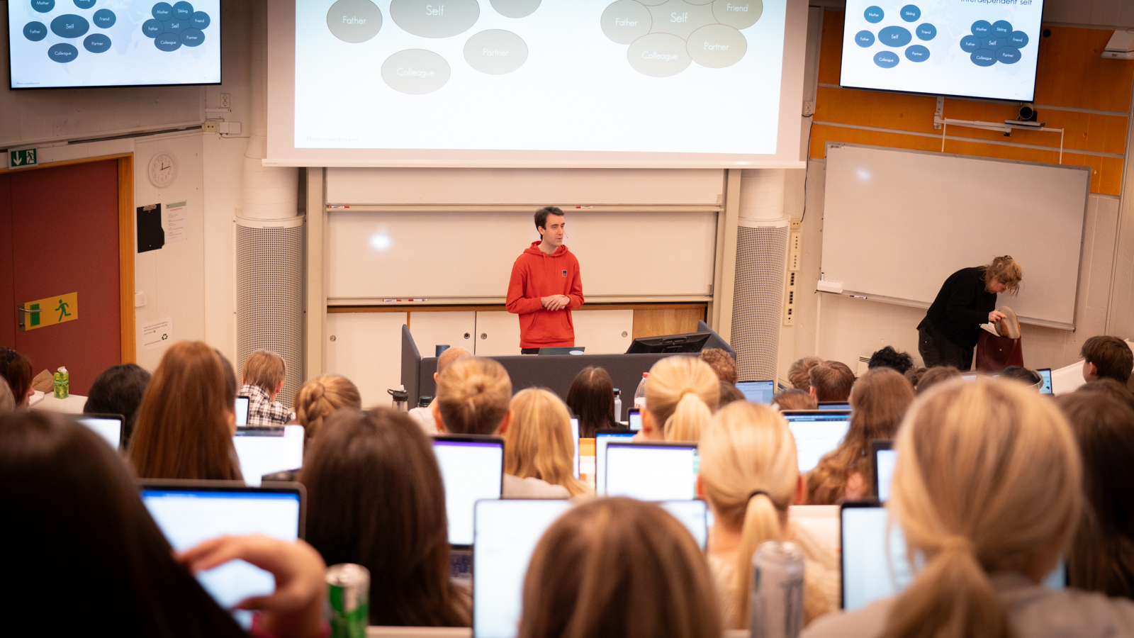 Stian in front of many students in an auditorium. He is giving a lecture