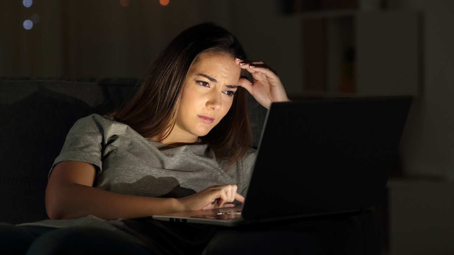 Jente sitter foran PC i mørket