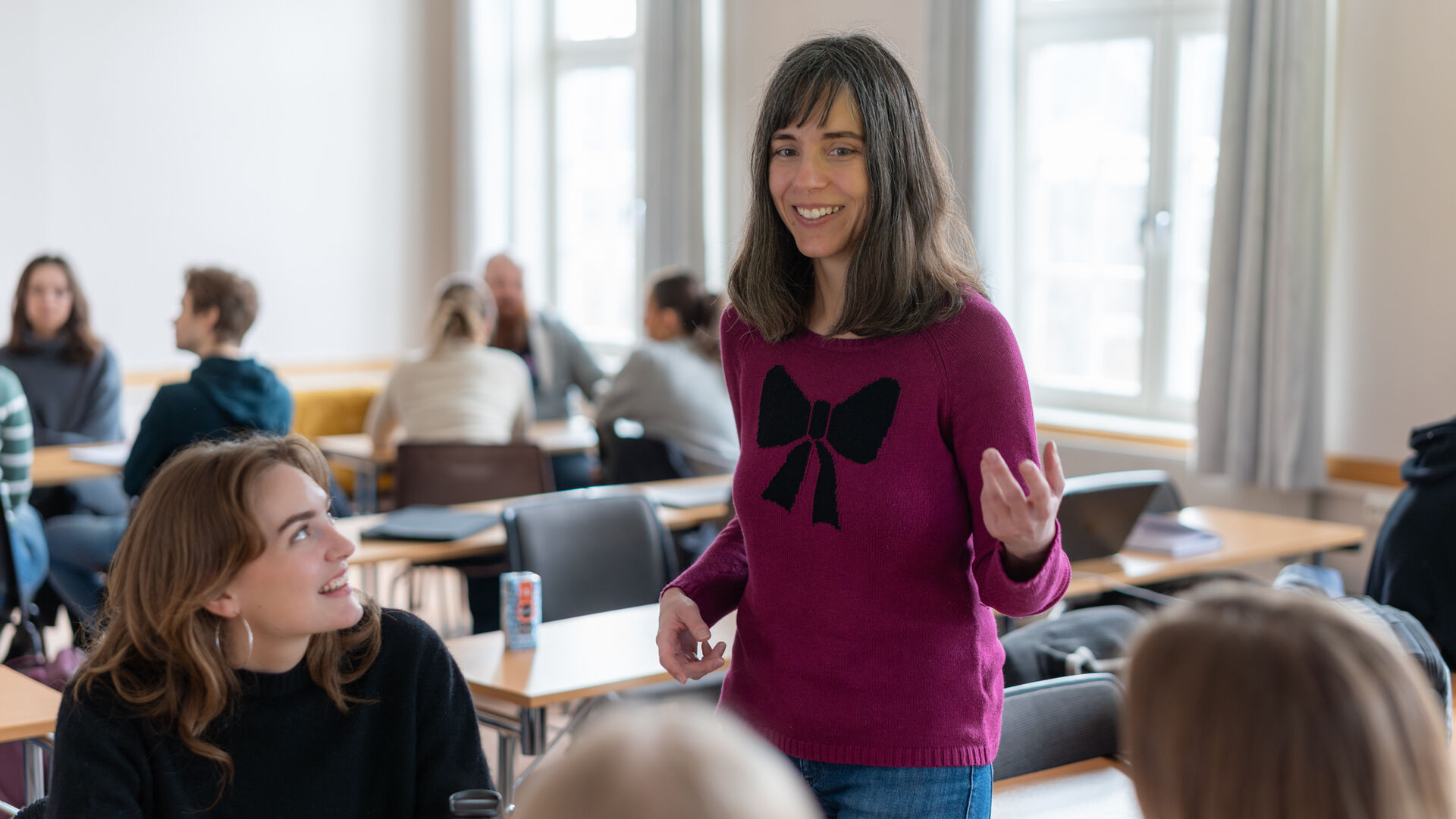 Dame står i et klasserom og snakker med studenter
