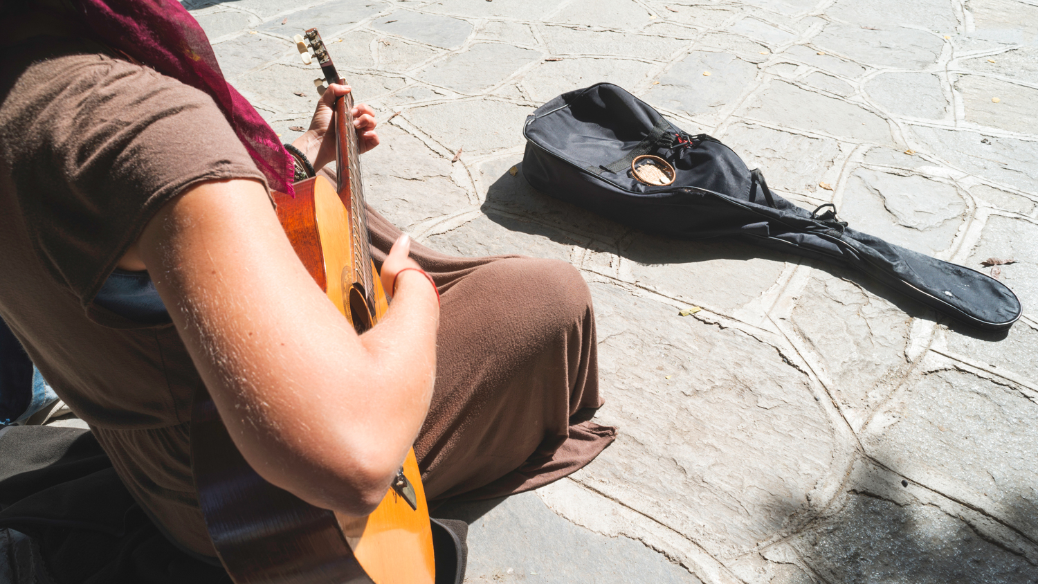 En gatemusikant med gitar og en kasse der forbipasserende har lagt småmynter