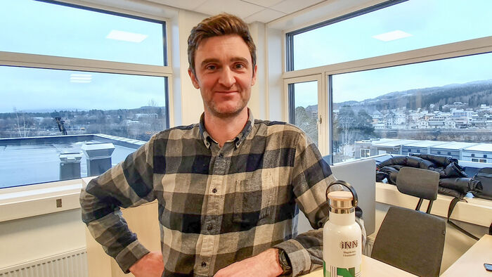 Bilde av Johan Kask stående på et kontor med store vinduer bak