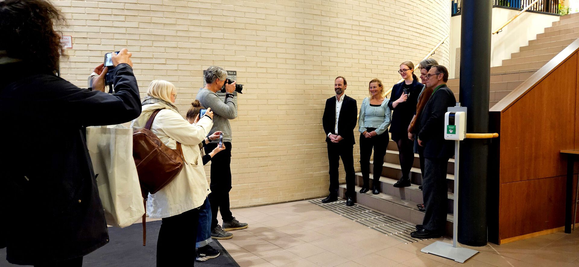 Hovedpersonene i disputasen står oppstilt, mens mange tar bilde av dem.