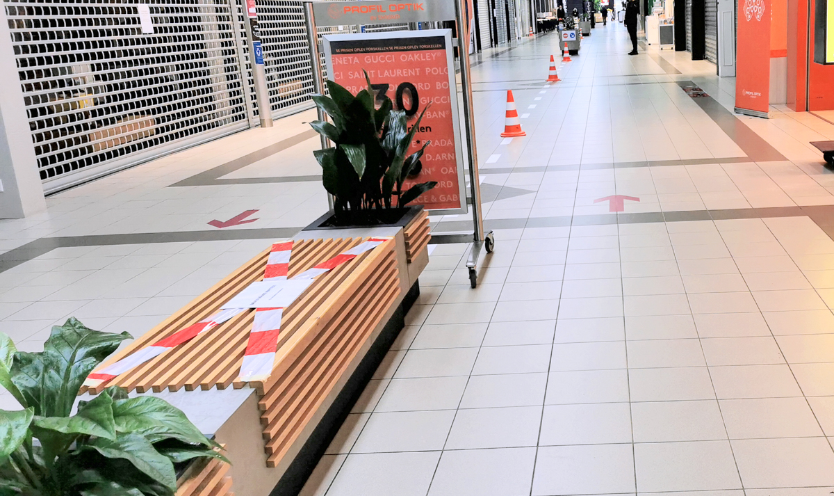 En gang på et stengt kjøpesenter under pandemien med sperrebånd og piler som viser hvor vi skulle gå