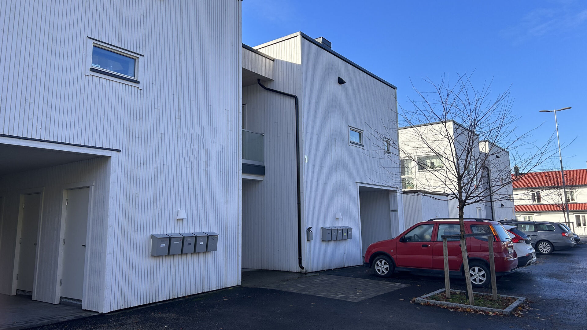 Bilde av utleielieiligheter i rekke. HVite hus med  biler parkert utenfor