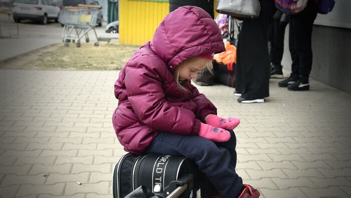 Agata 5 år, sitter på en koffert og ser trist ut