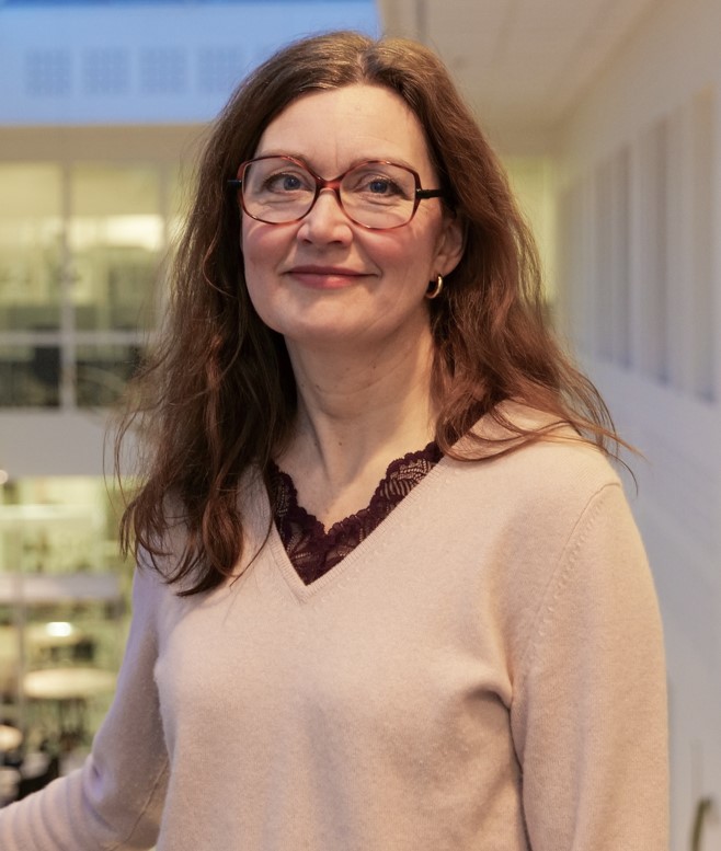 Marit Sletmoen mot noen kontorvidnuer og hvite vegger innendørs