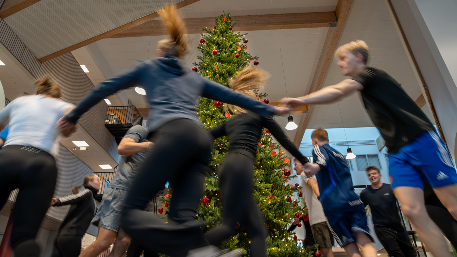 Ungdommer løper rundt et juletre i treningsutstyr