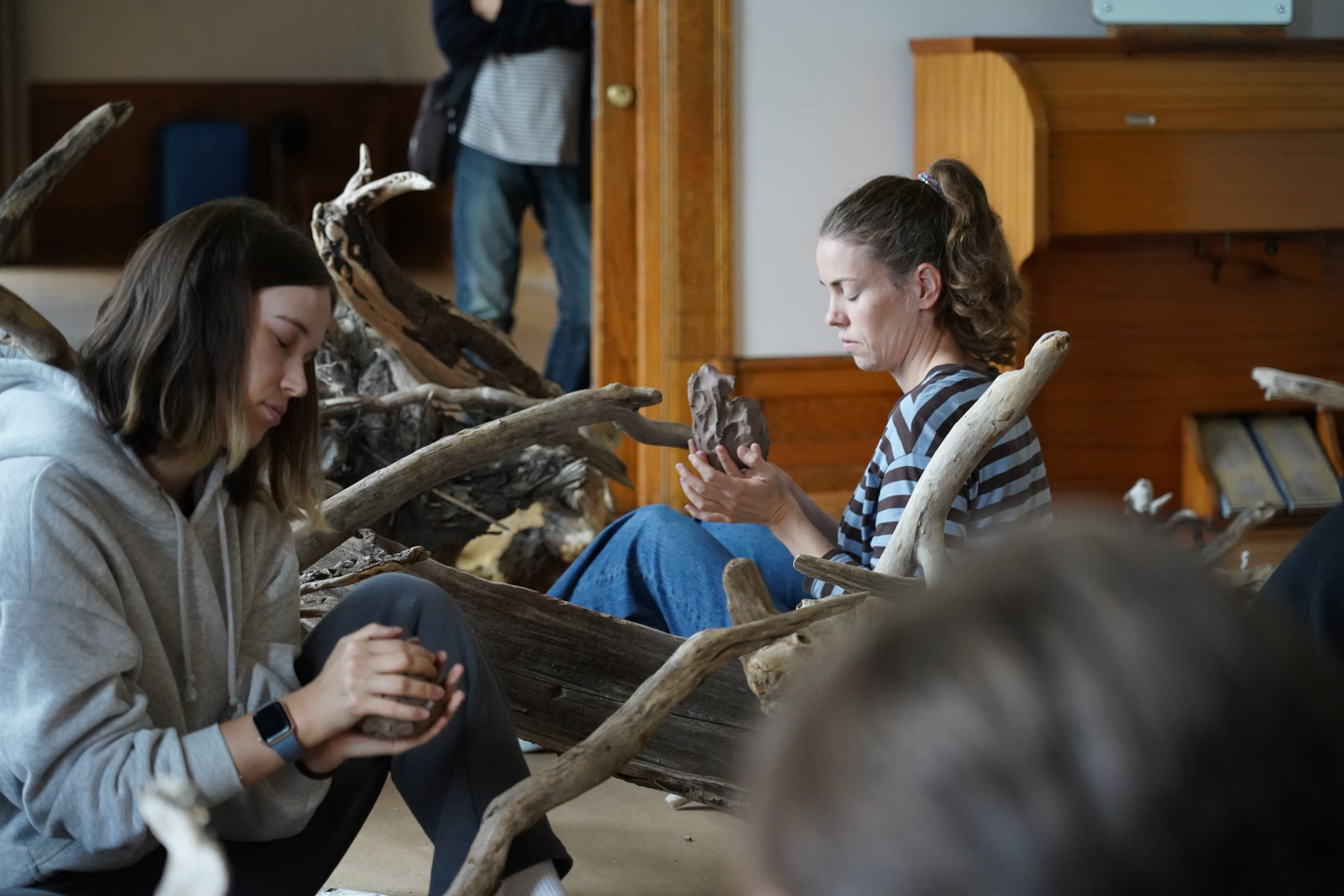 To damer sitter med leire i hendene på gulvet
