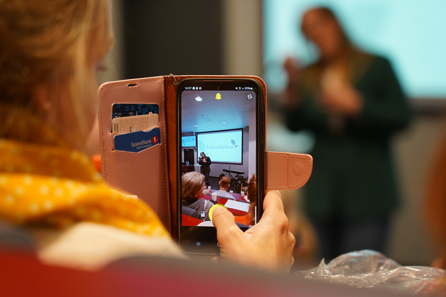 Bilde av en mobiltelefon som tar bilde av en sanger på en scene