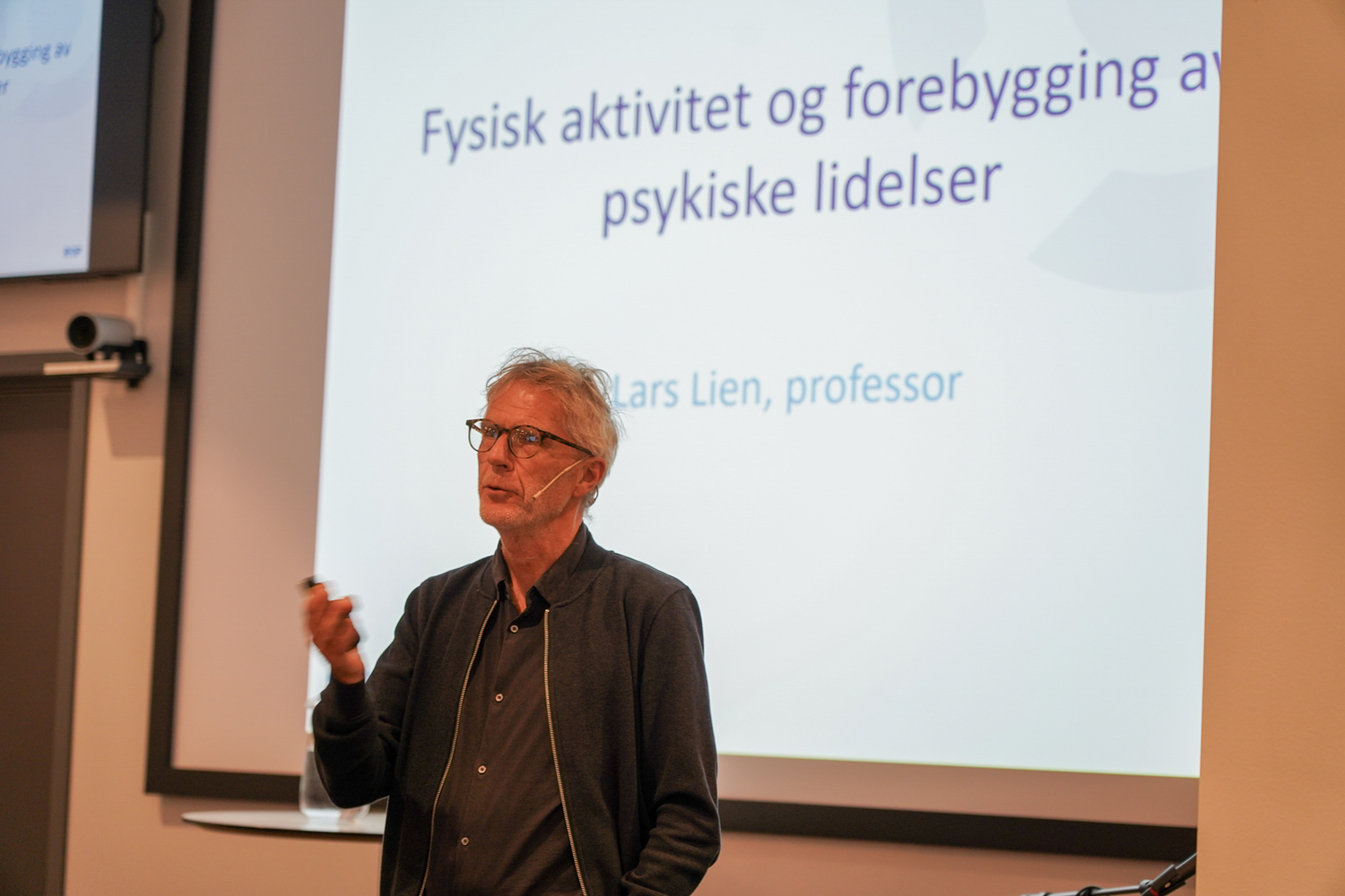 Professor foran lysbilde på en lys vegg