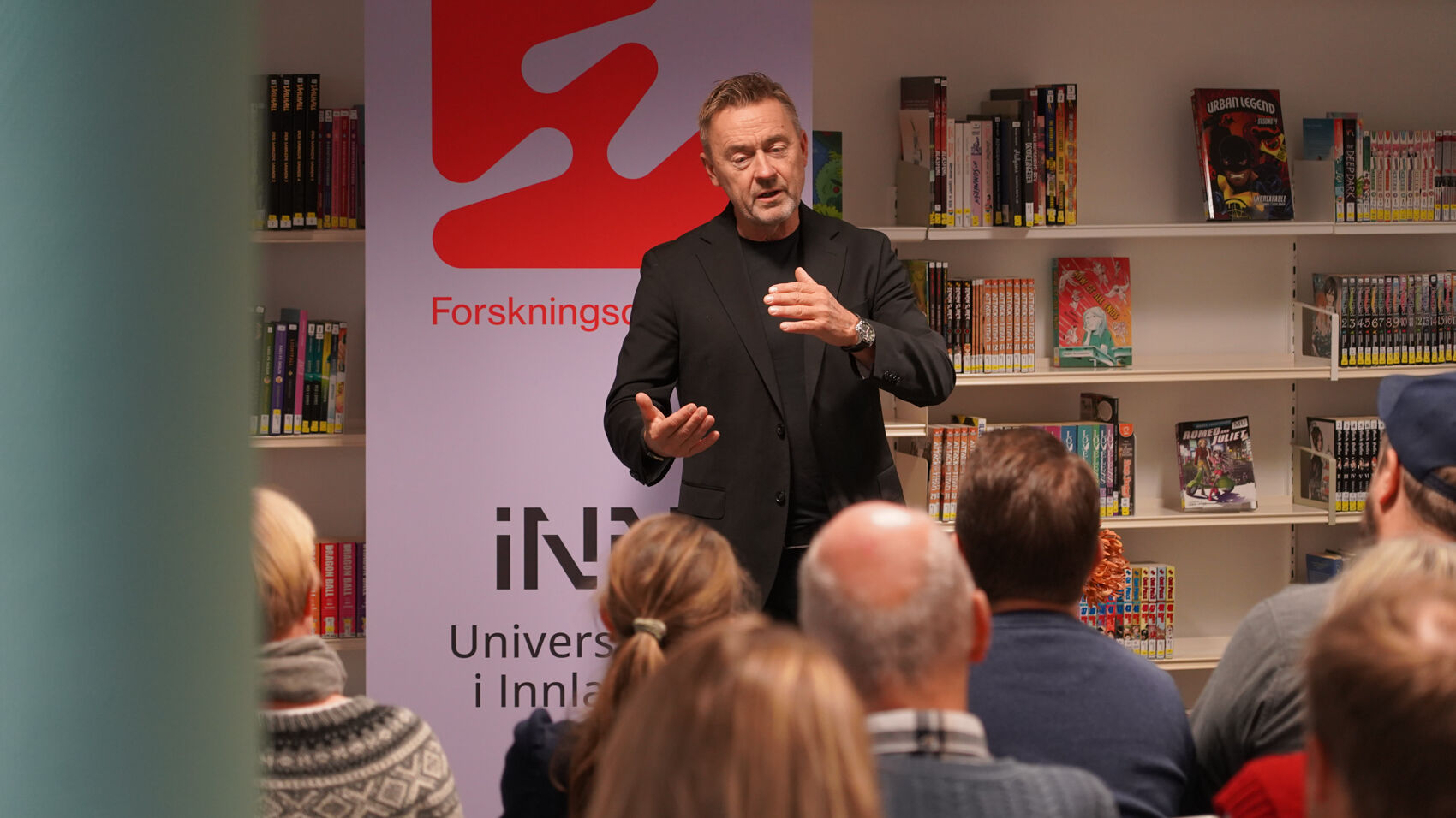 Mann står foran publikum på bibliotek