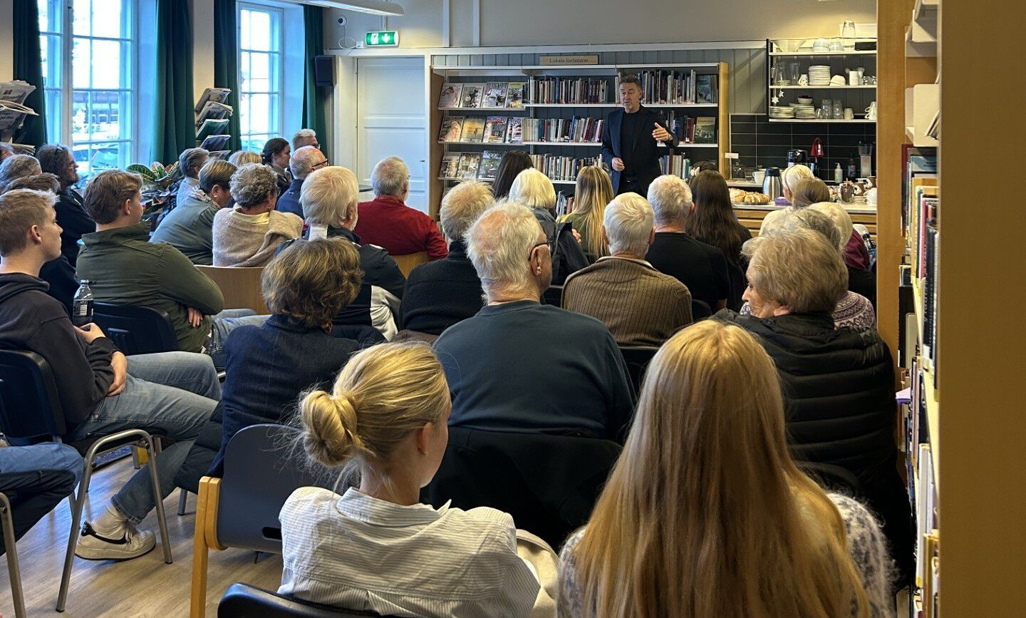 Mann står foran publikum på et bibliotek