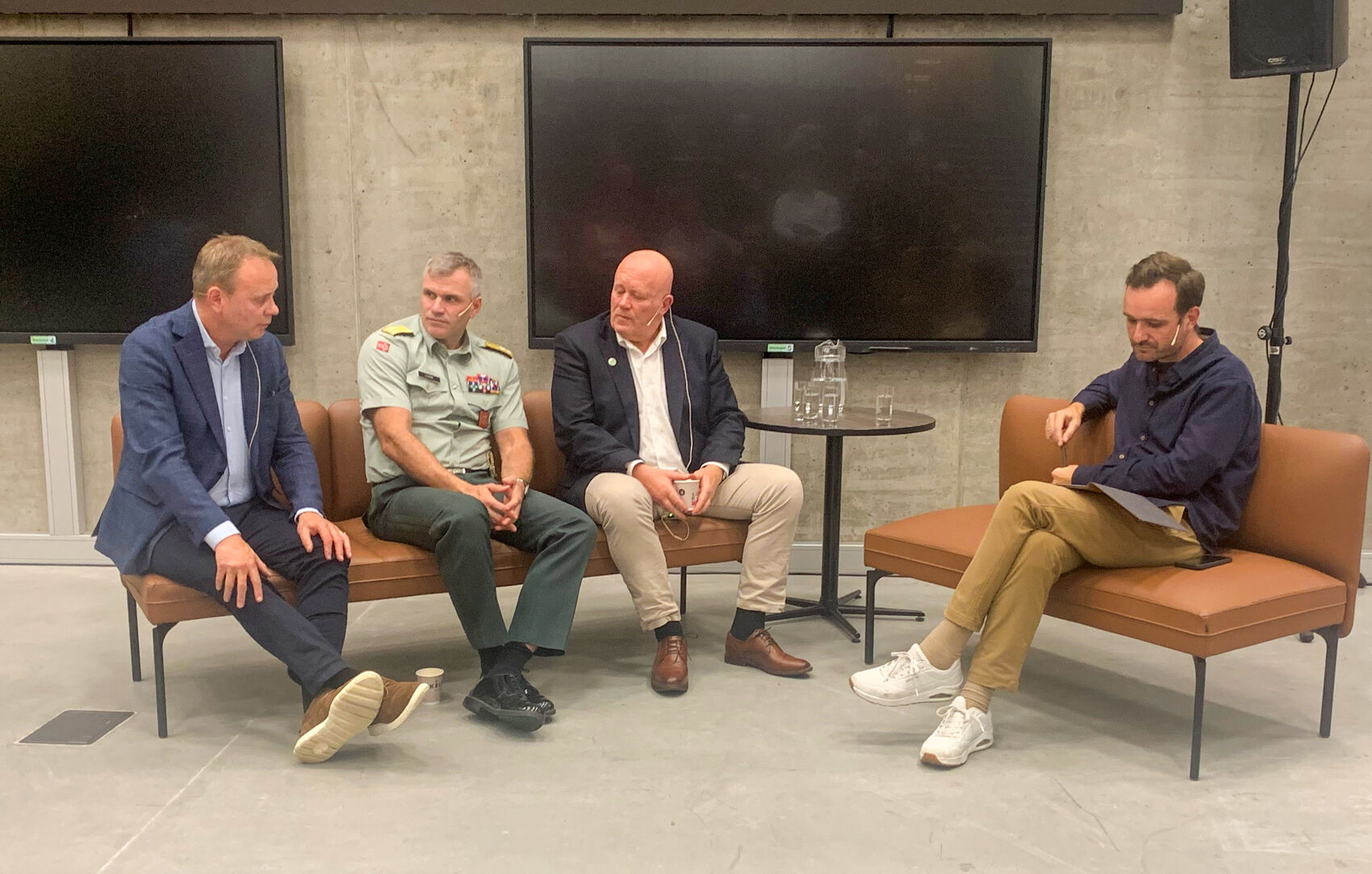 Fire menn sitter i en bunker med store skjermer på veggene