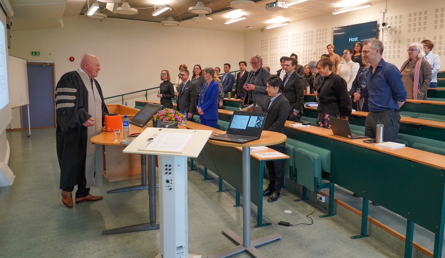 Rektor foran et auditorium med folk 