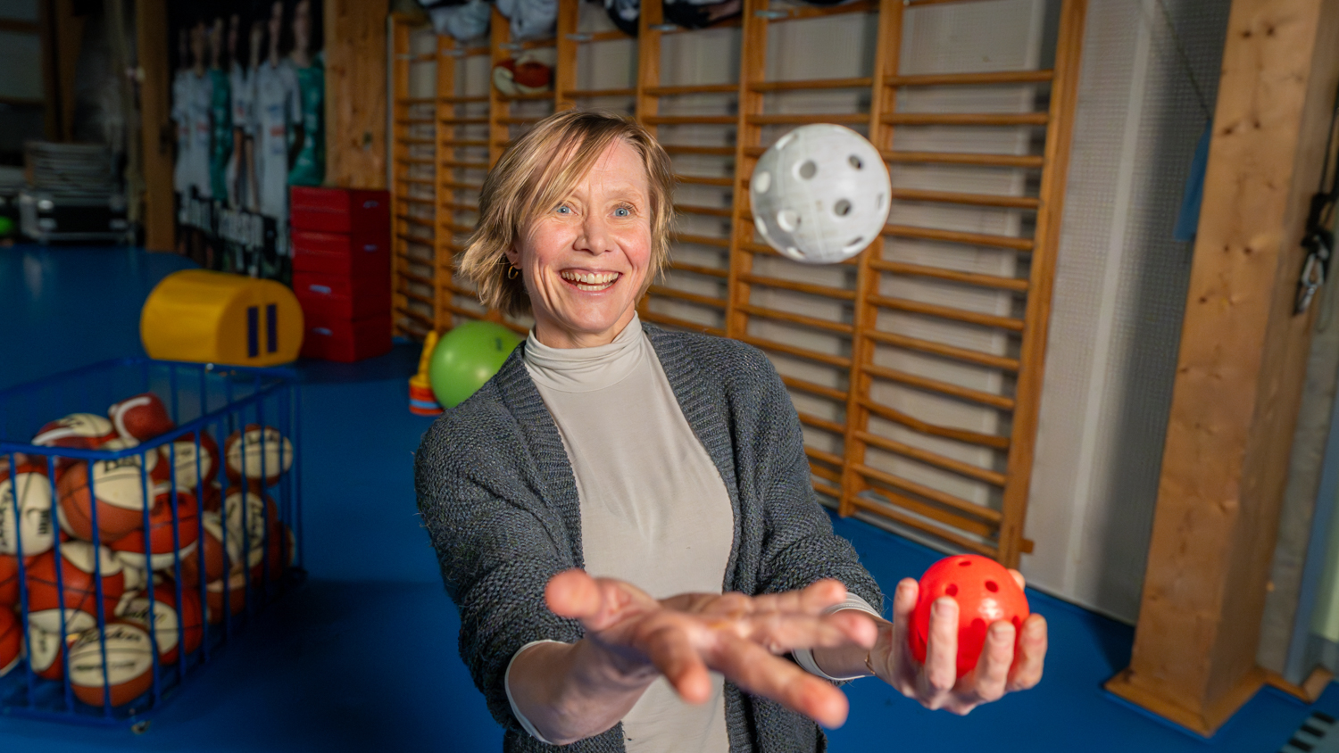 LInda Røset sjonglerer med baller i en gymsal foran en ribbevegg