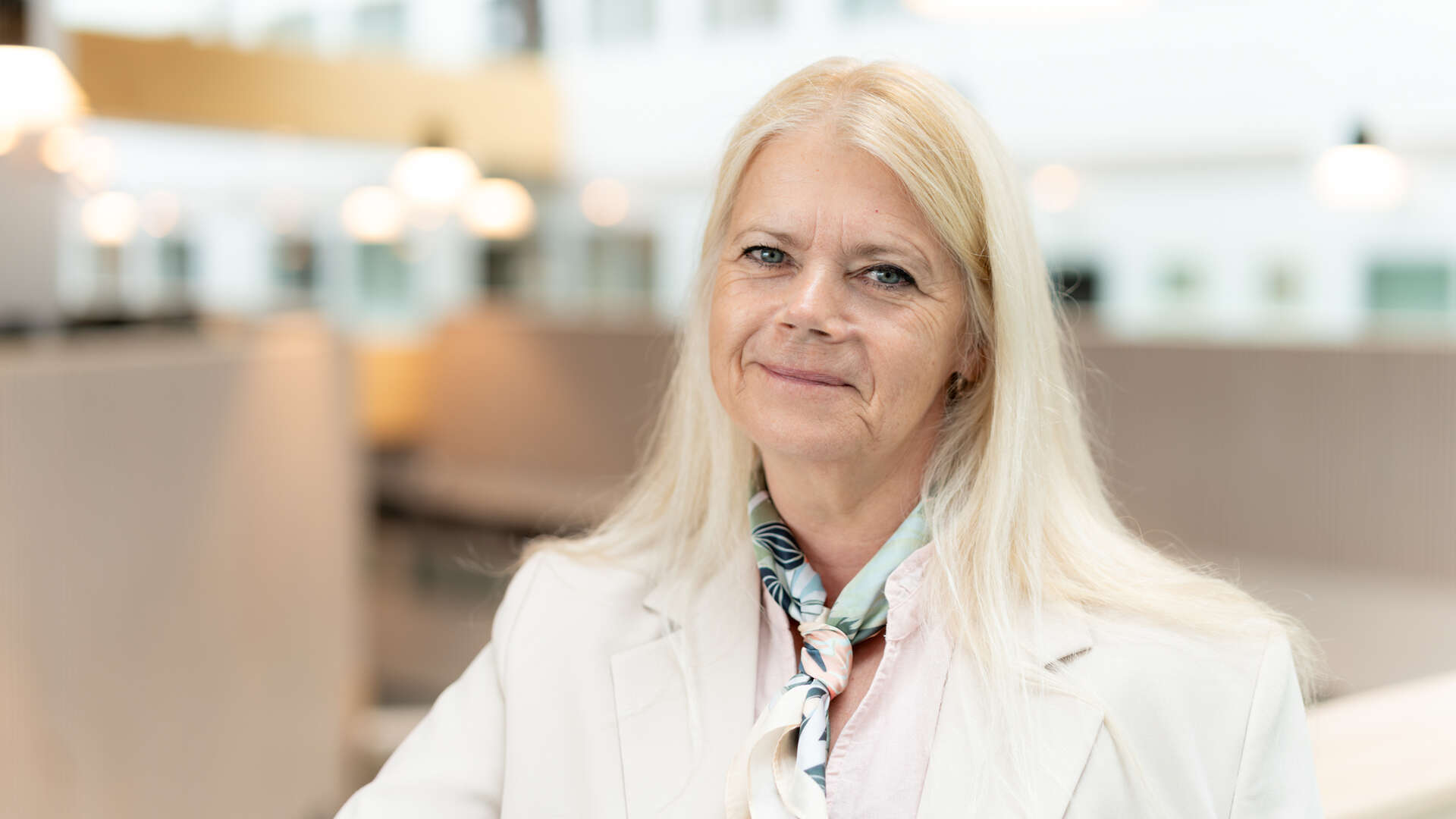 Portrettbilde av dame med hvit jakke og lyst, langt hår