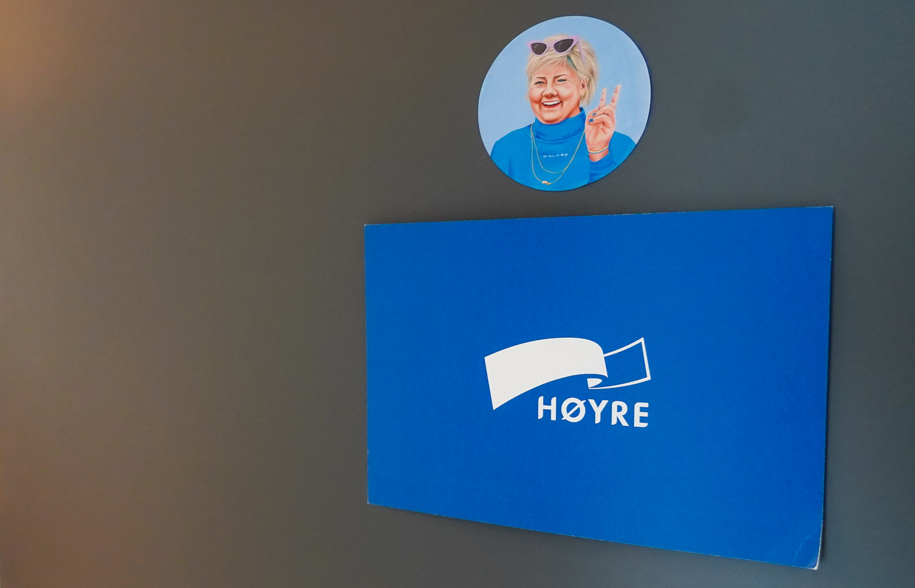 Høyreplakat med klistremerke av en smilende Erna på partikontordør.