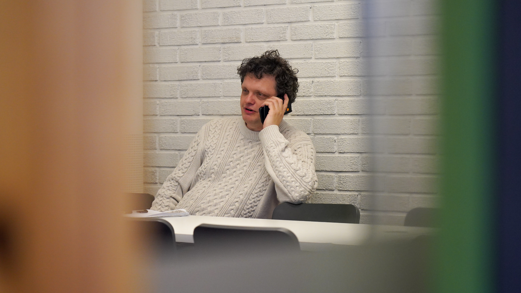 Valgforsker Tord Willumsen sitter ved et bord mens han snakker i telefonen.