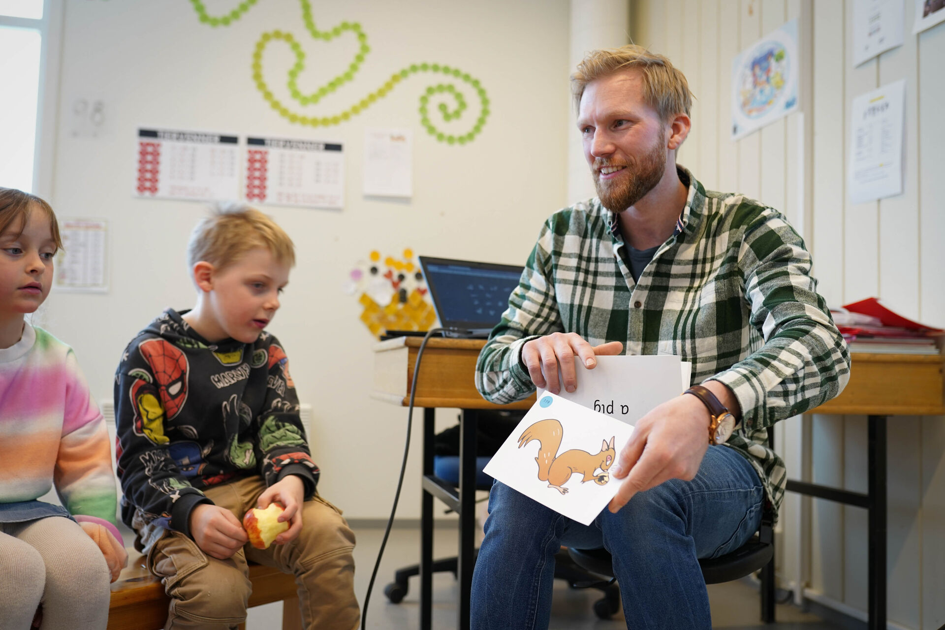 Halvor holder opp en tegning av et dyr og forteller barna som sitter rundt.