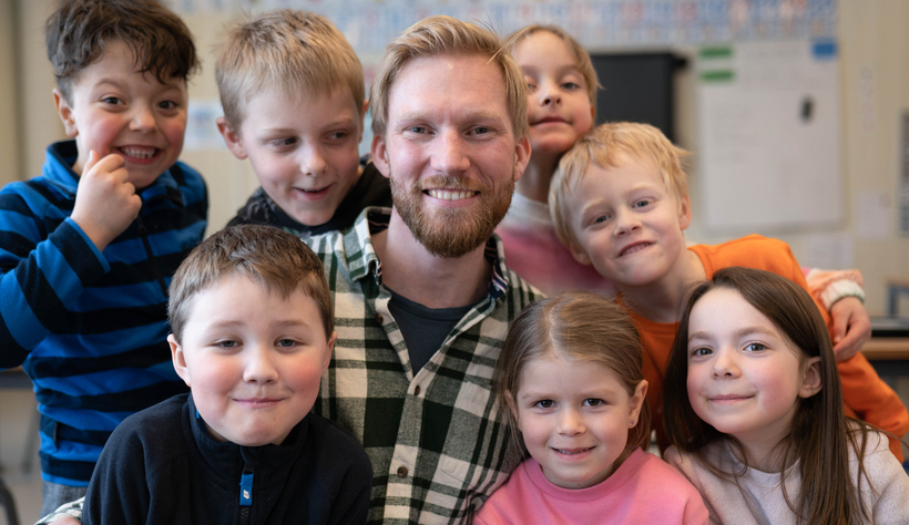 Læreren med barna rundt seg - nærbilde av ansikter.