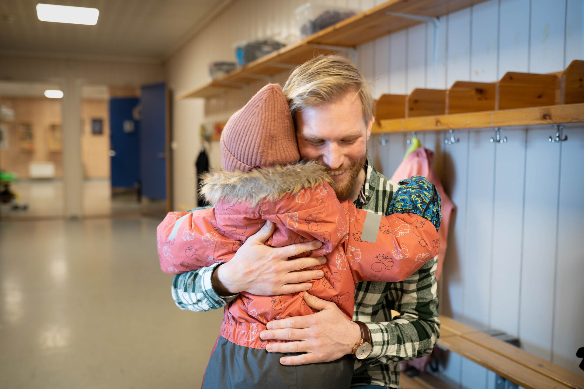 H får klem av en av elevene sine. Barnet står med ryggen til.