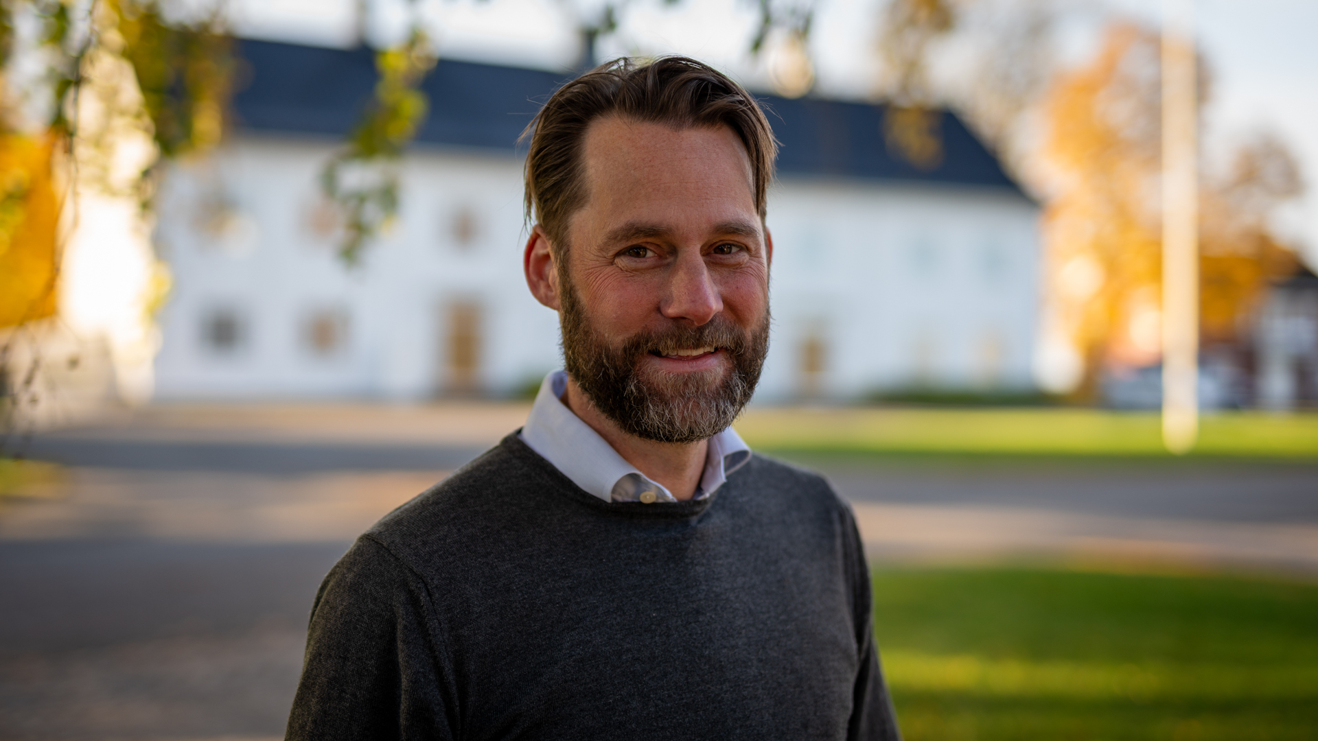 Portrettfoto av Micael Wendell med hvitt hus i bakgrunnen.